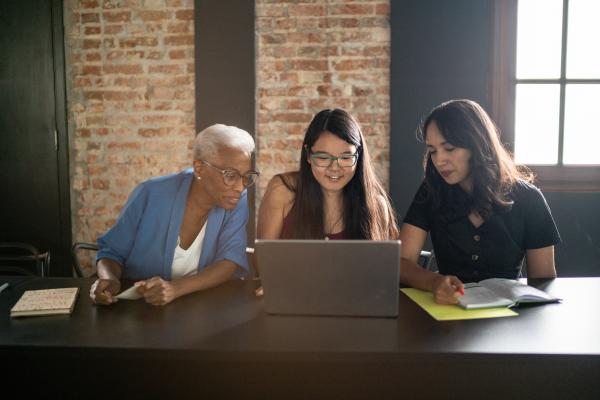 Three people of varying ages looking at a laptop screen