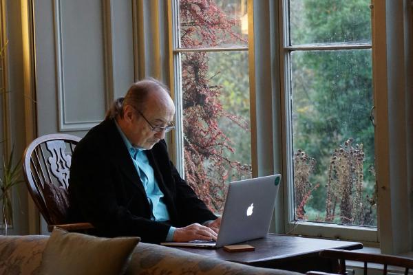 A person sits at a table using a laptop.