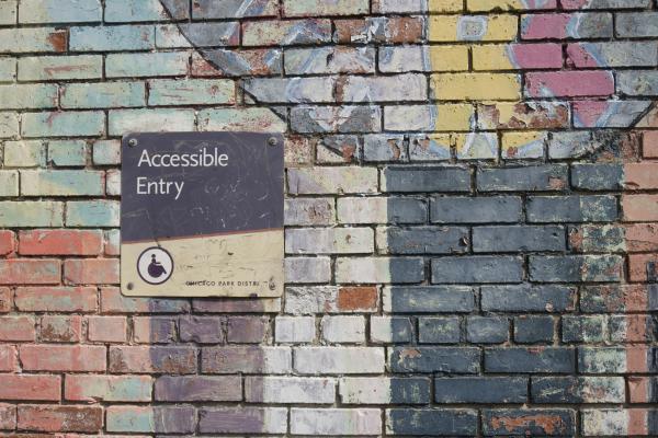 Photograph of a colorful brick wall with an Accessible Entry sign