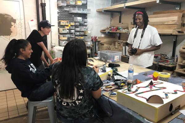 Photograph of four teens sitting around a workshop table designing tactile board games