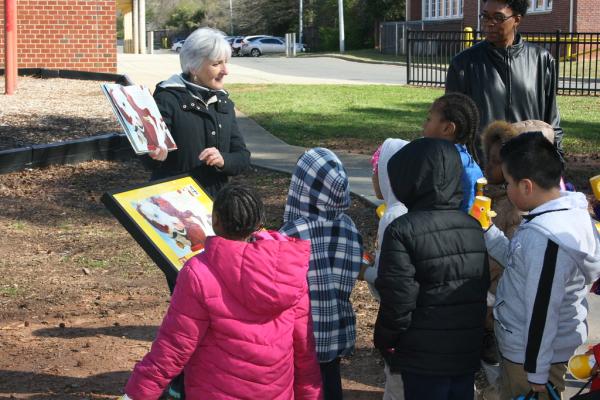 Photograph of librarian reading a story during a StoryWalk to a group of children.