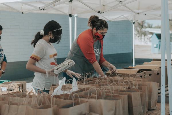 Volunteers putting food into paper bags at a food drive