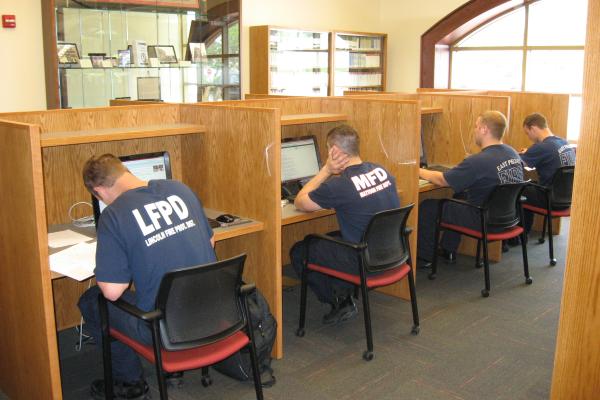 Photograph of firefighters using computer stations inside the Illinois Fire Service Institute Library