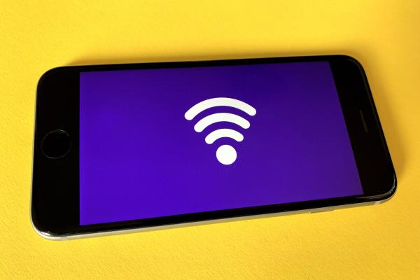 Photograph of iPhone with a wifi symbol on screen against a yellow background.