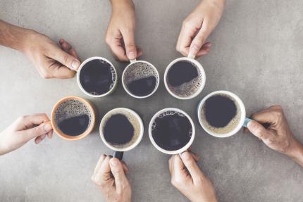 hands holding cups of black coffee