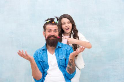 girl pointing and posing with dad after she gives him hilarious hairdo