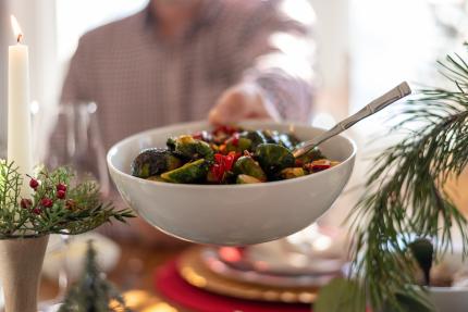 passing a dish of brussels sprouts at a festive holiday table