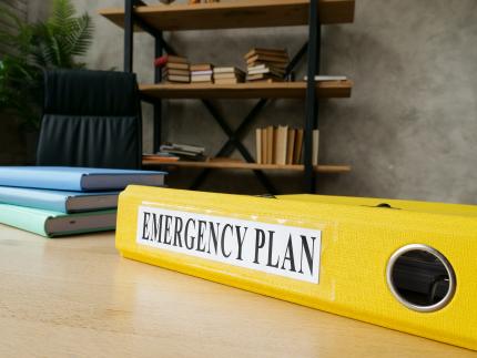 emergency plan in a yellow folder on a desk with other books