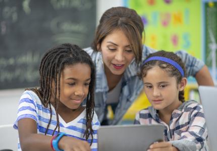 girls with teacher female teacher assisting two girls with technology education