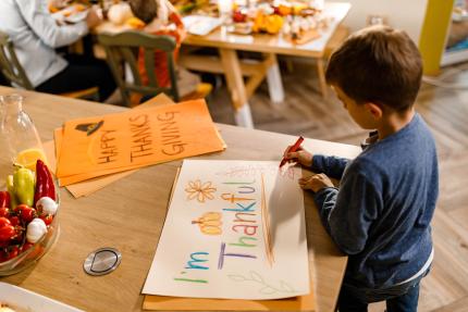 young boy drawing a colorful thankfulness poster