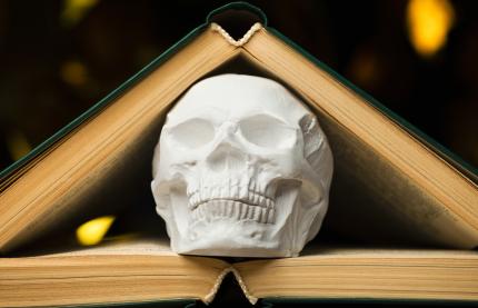 skull wedged between two books on dark glowy background