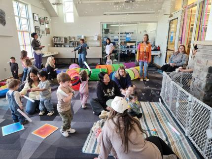 Babies and their caregivers dance around the Baby Rave room