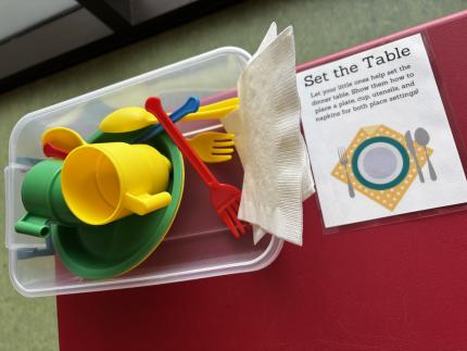 A photograph of the Set the Table station with napkins and plastic dishes.