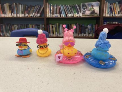 Four rubber ducks dressed up in small hats and other accessories.