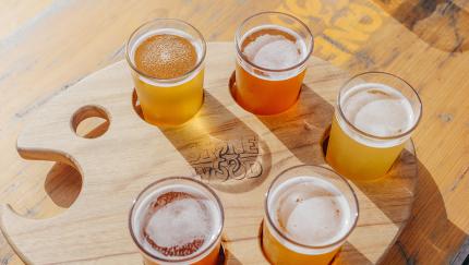 a flight of beers on a wooden tray