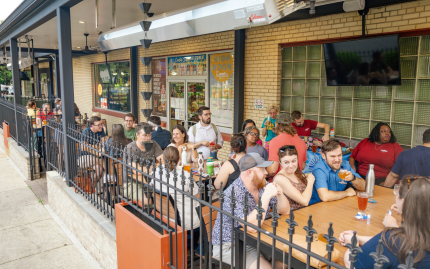 Photograph of people sitting at tables outside of a brewery