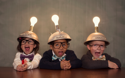 Photograph of three children dressed in smart clothing with caps and lit up lightbulbs on their heads.