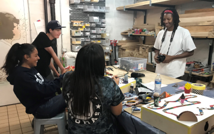 Photograph of four teens sitting around a workshop table designing tactile board games