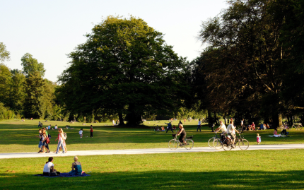 Photograph of a public park with people sitting, walking, and biking.