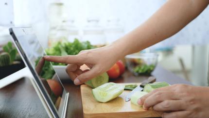 A cutting board with chopped vegetables and an iPad