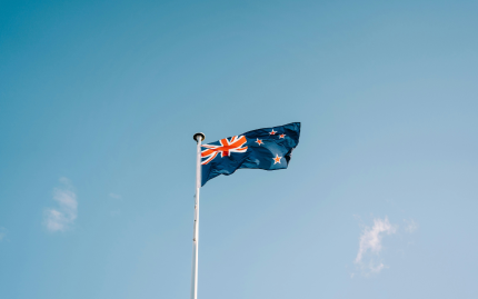 Photograph of the New Zealand flag against a blue sky. 