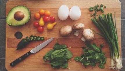 cutting board with vegetables being cut up with a knife