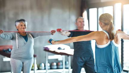 Two senior citizens are working out with a fitness trainer. 