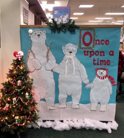Photograph shows the indoor entrance to the StoryWalk. Image shows a large poster with three polar bears. Text on the poster reads "Once upon a time"