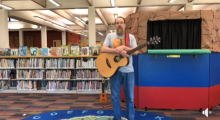 Man playing guitar in front of puppet theater