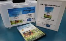 Photograph of a Film Discussion Kit for "The Biggest Little Farm." Photograph shows the DVD, Film Discussion Guide binder, and container.