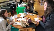 Woman sitting at table with little girl doing crafts