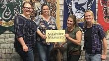Four people pose with "Mischief Managed" sign