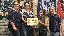 Four people pose with "Mischief Managed" sign