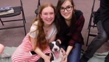 Two smiling girls pose with a happy puppy