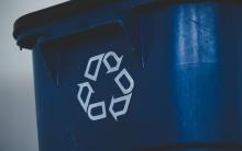 Photograph of blue recycling bin with the recycling logo.