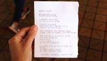 Hand holding paper with poem written on it