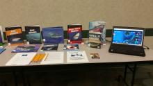 Materials on display at the "shark" themed station at the "I Survived" program Display of books about sharks and a laptop