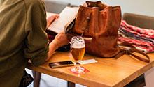 Shorts & Stouts Woman reading book next to glass of beer