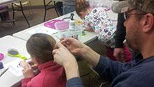A dad works on his daughter's hair A dad works on his daughter's hair