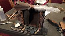 Fairy house created from slate, feathers and pinecones