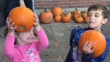 Two children holding pumpkins