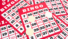 A pile of red and white bingo cards with some scattered bingo chips A pile of red and white bingo cards with some scattered bingo chips