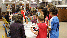 Kids gathered around a table making spectrocopes Kids gathered around a table making spectrocopes