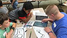 Three children playing with an Ozobot Three children playing with an Ozobot