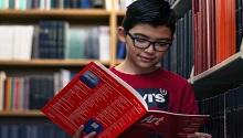 boy reading book in a library