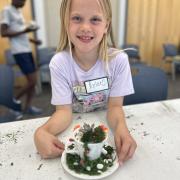 Photograph a child smiling showing a completed Fairy Garden