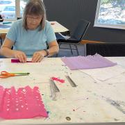 Photograph of a craft participant folding tissue paper
