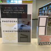 Photograph of flyer and film negative bookmarks. The flyer says: "If you lie this activity you may want to become a Photographer: a person who takes photographs or Cinematographer: A person responsible for the recording of a film, television production, music video or other live-action piece.