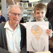 A senior poses with a child artist and their finished portrait