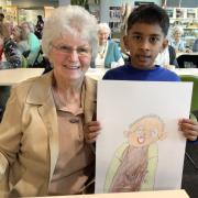 A senior poses with a child artist and their finished portrait